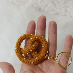 a hand holding a crocheted keychain with two rings attached to it