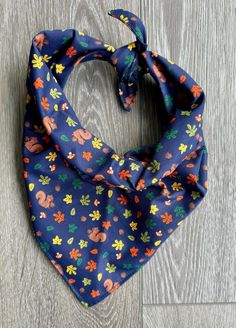 a blue bandana with flowers on it sitting on top of a wooden floor in front of a gray wall