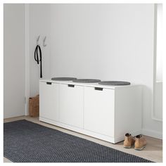 a pair of shoes sitting on top of a white cabinet next to a black rug