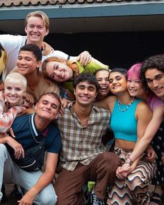 a group of young people posing for a photo in front of a building with their arms around each other