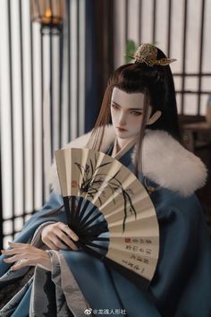 a doll dressed in traditional japanese clothing holding a fan