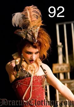 a woman in a red corset with feathers on her head holding a knife