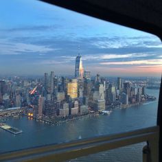 an aerial view of the new york city skyline at dusk from a plane window looking out over the water