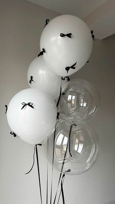 white balloons with black bows tied to them are in a vase on the floor next to a wall