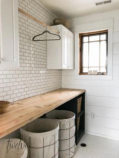 three trash cans sitting on top of a wooden counter in a white tiled kitchen area