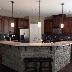 a kitchen with two stools in front of an island made out of stone blocks