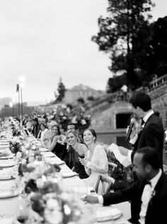 a group of people sitting at a long table with plates and glasses in front of them