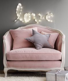 a pink chair with some pillows on it