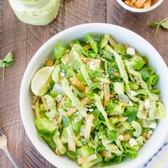 a white bowl filled with lettuce salad on top of a wooden table