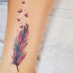 a woman's foot with a colorful feather and butterflies tattoo on the side of her leg