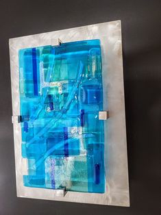 a piece of art made out of blue and white glass on a black surface with wires attached to it