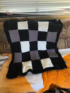 a black and white checkered blanket sitting on top of a couch next to pillows