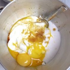 two eggs are in a metal bowl with yogurt