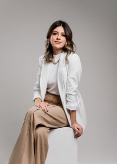 a woman sitting on top of a white box with her legs crossed and looking at the camera