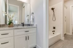 a bathroom with white cabinets and marble counter tops