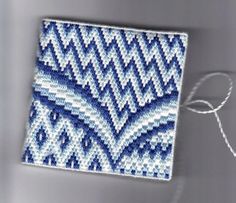 a piece of blue and white beaded fabric next to a string on a gray surface