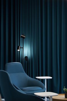 a blue chair and table in front of a curtained wall with lights on it