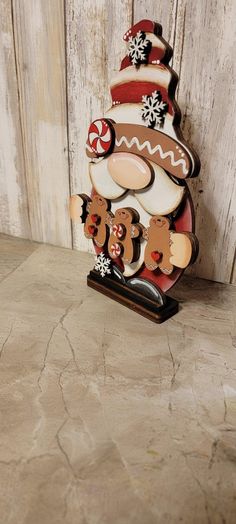 a wooden christmas tree with gingerbreads and bears on it's head, standing next to a wall