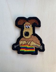 a dog with a rainbow in its mouth on a white surface, it appears to be made out of woven material