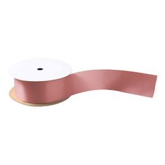 a roll of pink satin ribbon on a white background