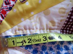 a measuring tape sitting on top of a piece of fabric next to a patchwork quilt