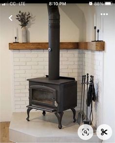 a black stove sitting in the middle of a room next to a white brick wall