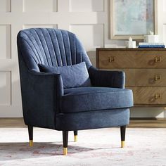 a blue chair sitting on top of a rug next to a dresser and chest of drawers