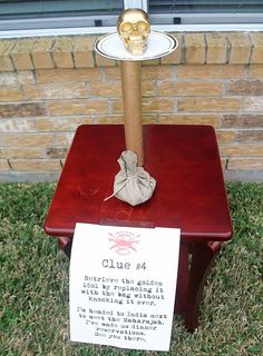 a small wooden table with a sign on it and a paper skull hanging from the top