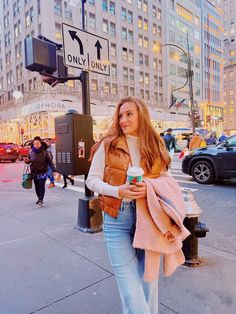 a woman walking down the street holding a cup of coffee