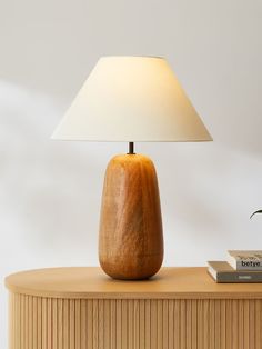 a wooden table with a lamp on top of it next to a book and a plant