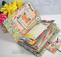 a stack of notebooks sitting on top of a table next to flowers and scissors