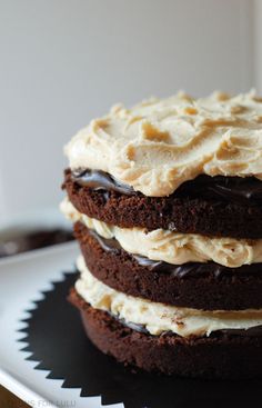 a chocolate cake with white frosting and brown icing stacked on top of each other