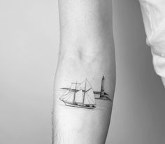 a black and white photo of a sailboat on the water with a lighthouse in the background