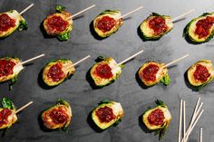 several small appetizers with toothpicks in them on a black table top