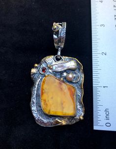 "Artisan Amber gemstone pendant Hand-made Sterling Silver 925,24k Gold Stones used: Baltic Amber, Pearls, Garnet Height - 3\" (with bail), Width - 1 1/2\" Height -75mm (with bail), Width - 38mm Unique Handcrafted One-of a-kind Design Pendant Each Piece of Jewelry in my Collection is Absolutely One of a Kind! When you start wearing a piece of my jewelry you will fall in love with it more and more each day and feel that good Energy and Love that I pass into it while creating this piece of Art. A p Unique Polished Pendant Necklace, Unique Amber Necklace With Polished Finish, Artistic Polished Pendant Necklaces, Artistic Pendant Necklace With Polished Finish, Hand Forged Amber Sterling Silver Jewelry, Artistic Polished Pendant Necklace, Artisan Yellow Gold Collectible Jewelry, Artistic Gold Jewelry With Cabochon, Antique Yellow Pendant Jewelry