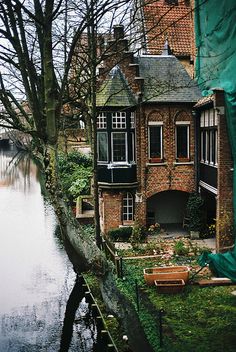 an old brick house next to a body of water