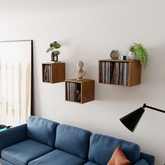 a blue couch sitting in a living room next to a wall mounted shelf with records