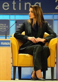 a woman sitting in a yellow chair with her legs crossed on the table next to a microphone