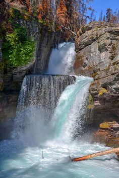 a large waterfall with water coming out of it's sides and trees in the background