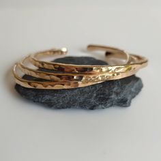 Build your own set! Add two or more items to your cart and enter the code: MOREMETAL during checkout for 15% off of your whole order! These beautiful handmade bronze bangle bracelets are a perfect addition to the MorrisMetalWork lineup! Bangles have been a staple item for this shop since the beginning, and I am proud to offer these hammered bronze bangles to you. The hammered texture on each bangle catches and reflects the light making these bracelets dazzling. This makes them perfect as an 8th anniversary gift for your wife, or a perfect gift for spoiling yourself.  These stacking bangles are formed into an oval shape for comfort, and are meant for a wrist size of about 7 inches. However, you can make them slightly smaller or larger by firmly pressing the ends together, or by pulling them Luxury Bronze Jewelry For Anniversary, Gold Metal Wrap Bracelet Bangle, Rose Gold Brass Bangle, Elegant Bronze Bangle As Gift, Adjustable Brass Bangle Gift, Adjustable Brass Bangle As Gift, Handmade Gold Cuff Bracelet For Everyday, Everyday Handmade Gold Cuff Bracelet, Nickel-free Bronze Bangle Bracelet