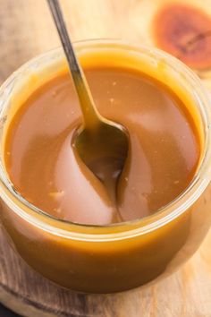 a spoon in a glass jar filled with caramel sauce on top of a cutting board