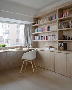 a home office with bookshelves, desk and chair in front of the window