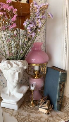 there is a vase with flowers in it next to a lamp and books on the table