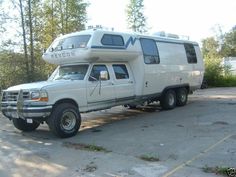 an rv parked in a parking lot next to trees