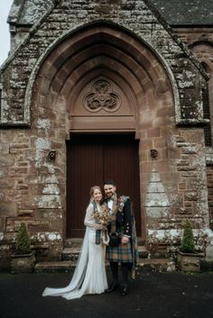 a bride and groom standing in front of an old church