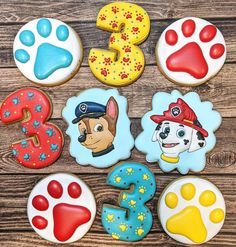 decorated cookies are arranged in the shape of numbers and paw patrol characters on a wooden surface