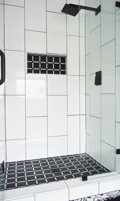 a bathroom with black and white tiles on the shower wall