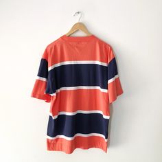 Vintage Tommy Hilfiger navy and orange striped t-shirt with embroidered logo on the pocket. 100% cotton. Size L Measurements: Length: 29 inches Pit to pit: 23 inches In good vintage condition. Summer Polo Shirt With Horizontal Stripes, Summer Horizontal Stripe Polo Shirt, Summer Short Sleeve Horizontal Stripe Polo Shirt, Cotton Polo Shirt With Vertical Stripes, Cotton Short Sleeve Polo Shirt With Vertical Stripes, Striped Cotton Polo Shirt With Relaxed Fit, Casual Short Sleeve Tops With Signature Stripes, Casual Short Sleeve Polo Shirt With Horizontal Stripes, Casual Horizontal Stripe Short Sleeve Polo Shirt