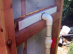 a white pipe is attached to the side of a window sill in front of a house