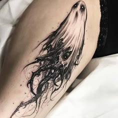 a woman's thigh with an octopus tattoo on her leg and the legs are black and white